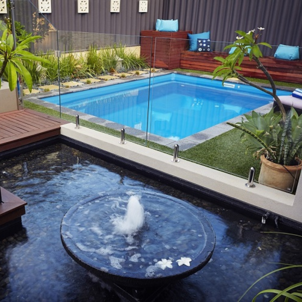 Full Billabong Plunge 6.5m installed with a water feature, frameless glass fencing and exterior landscaping