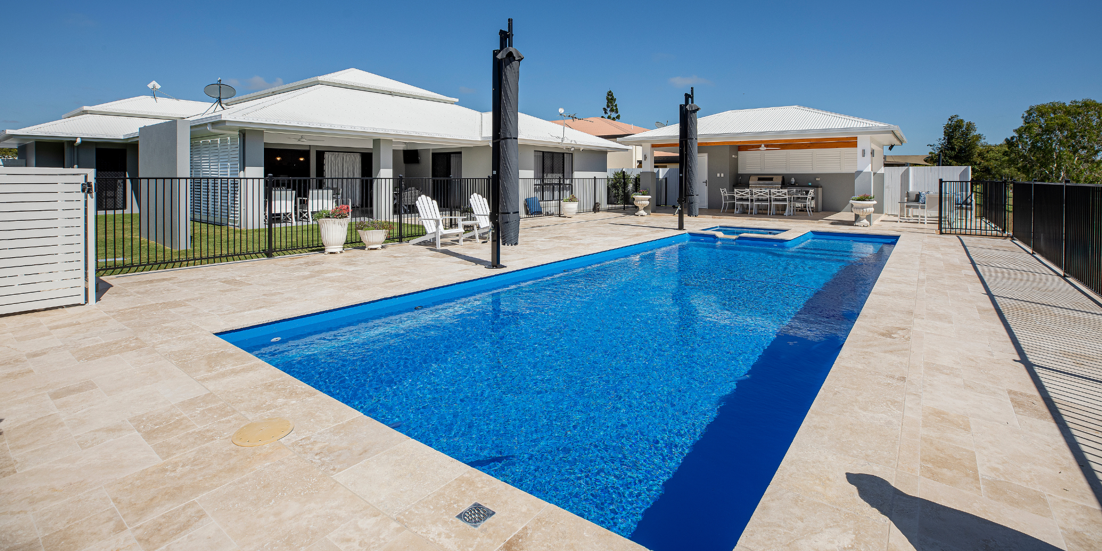 Swimming pool in a backyard with a house and trees in the background