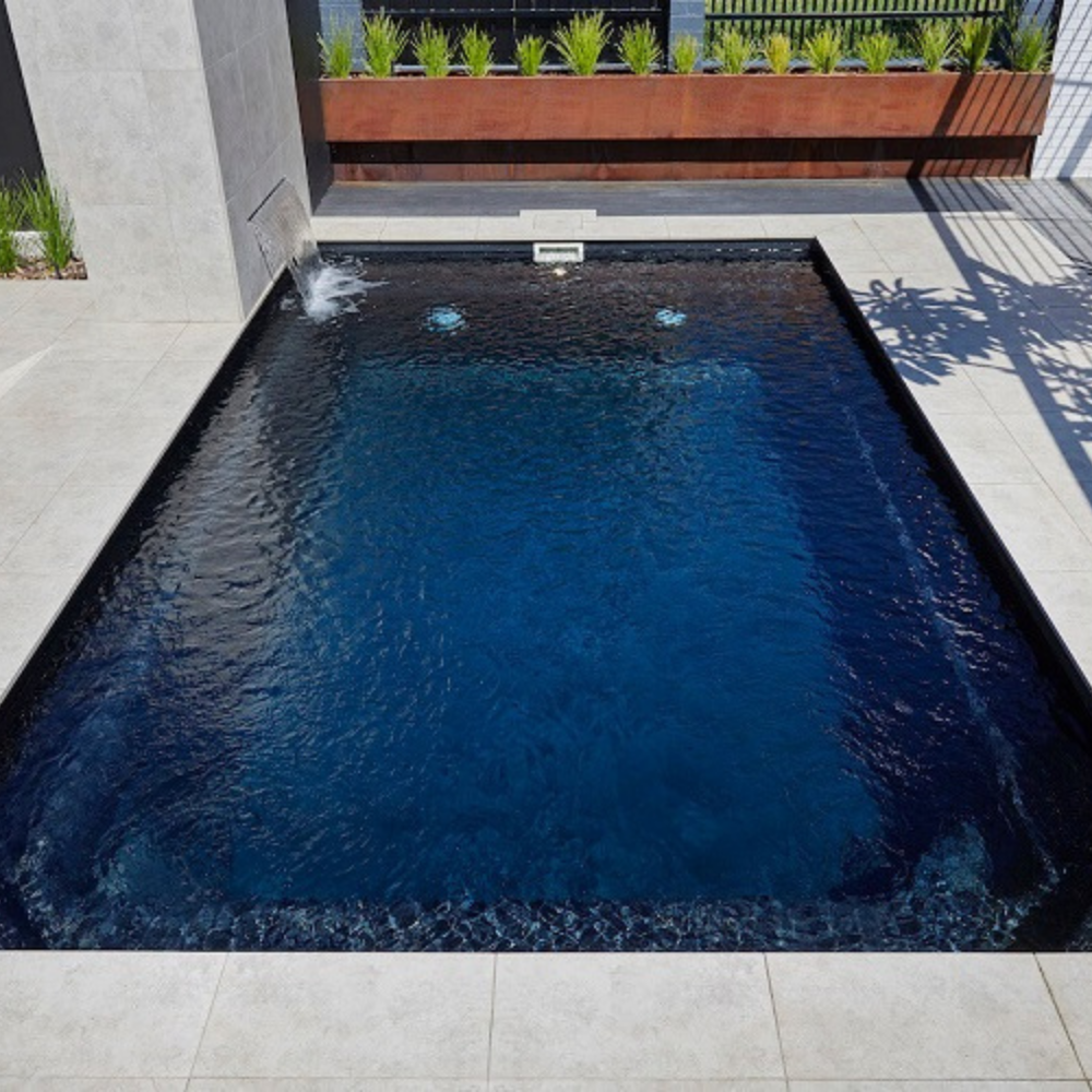 Billabong Plunge 4.7m in midnight Shimmer installed with light grey tiles and a corner water feature 
